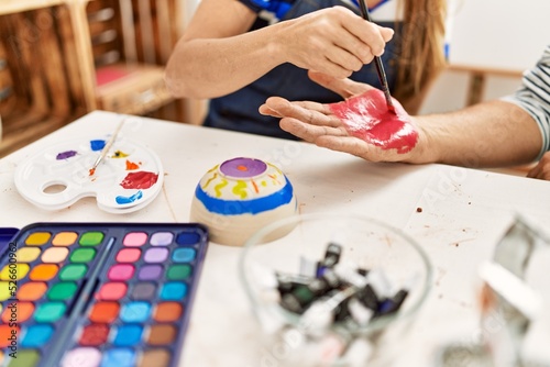 Couple painting hands at art studio.