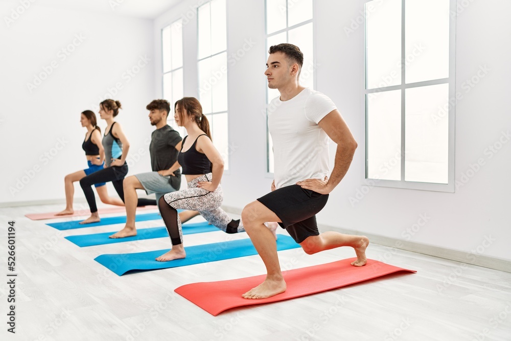 Group of young hispanic people concentrate training yoga at sport center.