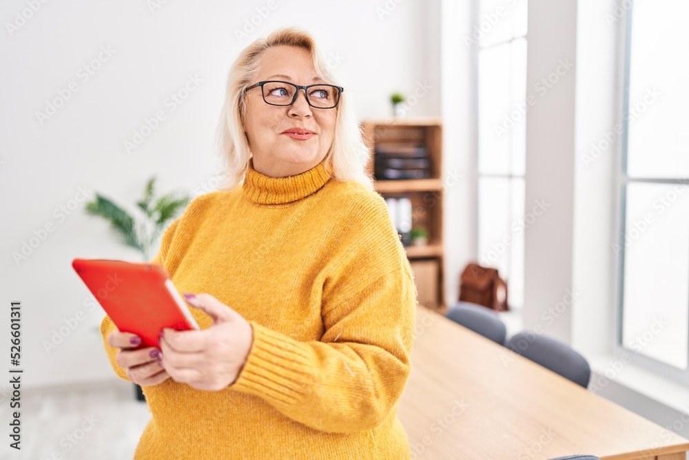 Middle age blonde woman business worker using touchpad at office Middle age blonde woman business worker using touchpad at office