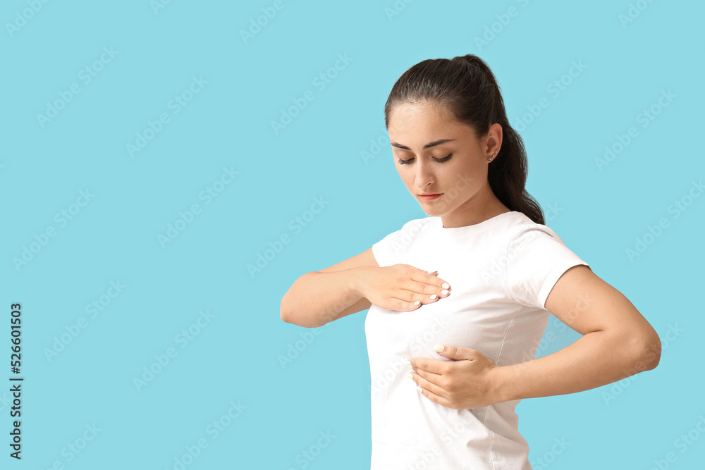 Young woman suffering from breast pain on blue background Young woman suffering from breast pain on blue background