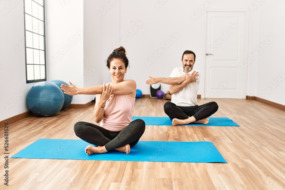 Mature hispanic couple doing excersice and stretching at yoga room. Two adult people doing pilates and flexibility workout Mature hispanic couple doing excersice and stretching at yoga room. Two adult people doing pilates and flexibility workout