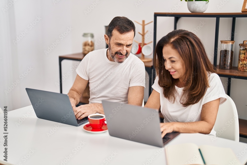 Middle age man and woman couple working sitting on table at home Middle age man and woman couple working sitting on table at home