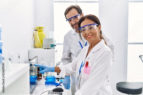 Middle age man and woman partners wearing scientist uniform working at laboratory