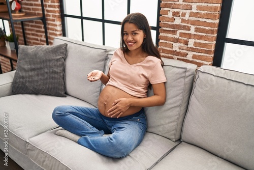 Young latin woman pregnant holding pills at home