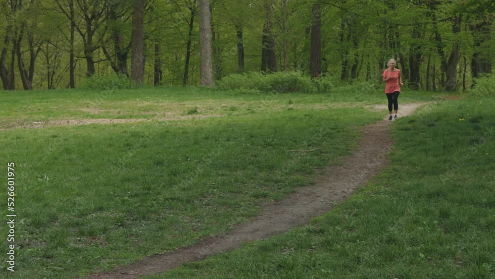senior woman running jogging in green park, elderly retired female in pink sportswear doing cardio outdoors. training workout woman runs in forest. active lifestyle concept, happy retired woman jogger senior woman running jogging in green park, elderly retired female in pink sportswear doing cardio outdoors. training workout woman runs in forest. active lifestyle concept, happy retired woman jogger