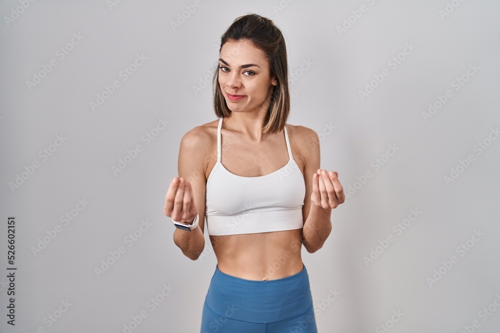 Hispanic woman wearing sportswear over isolated background doing money gesture with hands, asking for salary payment, millionaire business Hispanic woman wearing sportswear over isolated background doing money gesture with hands, asking for salary payment, millionaire business