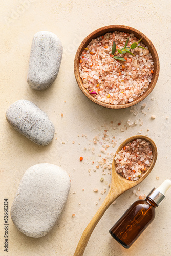 Bowl with sea salt, bottle of essential oil and spa stones on light background