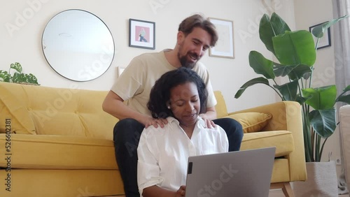 Happy and affectionate heterosexual couple looking at the laptop shopping online in an apartment.