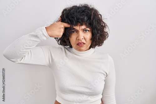 Hispanic woman with curly hair standing over isolated background pointing unhappy to pimple on forehead, ugly infection of blackhead. acne and skin problem © Krakenimages.com