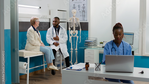 African american medic consulting senior patient in cabinet, talking about healthcare treatment and medicine to cure disease. Woman and doctor doing checkup visit examination at clinic.