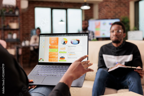 African american business people analyzing company charts and diagrams on laptop to create startup presentation and paperwork report. Doing teamwork collaboration to plan research information.