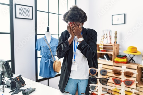 African young woman working as manager at retail boutique with sad expression covering face with hands while crying. depression concept.