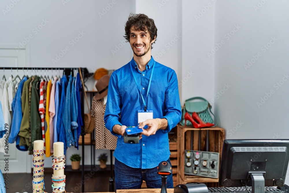 Young hispanic man paying using dataphone and credit card at clothing store Young hispanic man paying using dataphone and credit card at clothing store