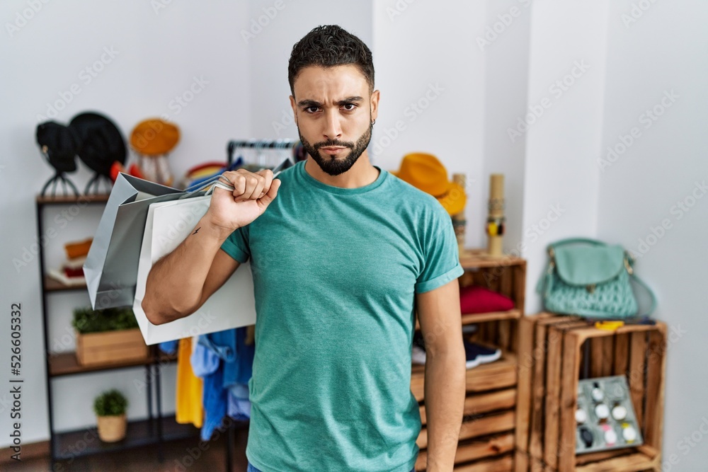 Young handsome man with beard holding shopping bags at retail shop skeptic and nervous, frowning upset because of problem. negative person. Young handsome man with beard holding shopping bags at retail shop skeptic and nervous, frowning upset because of problem. negative person.