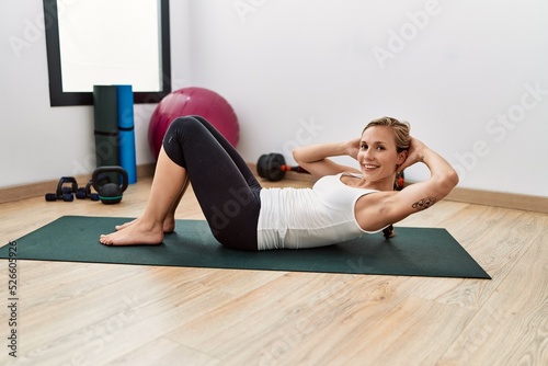 Young caucasian woman smiling confident training abs exercise at sport center