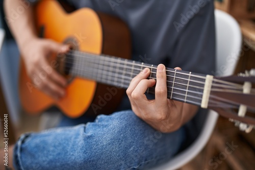 Young caucasian man playing classical guitar at home