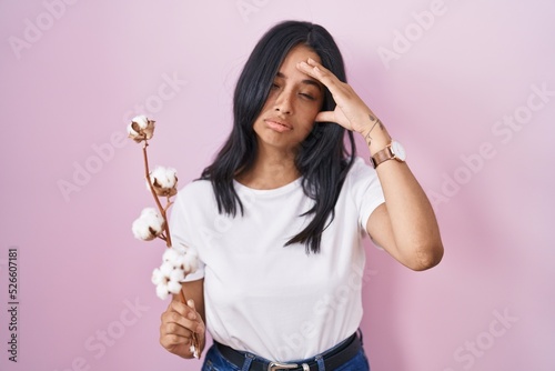 Brunette woman standing over pink background worried and stressed about a problem with hand on forehead, nervous and anxious for crisis