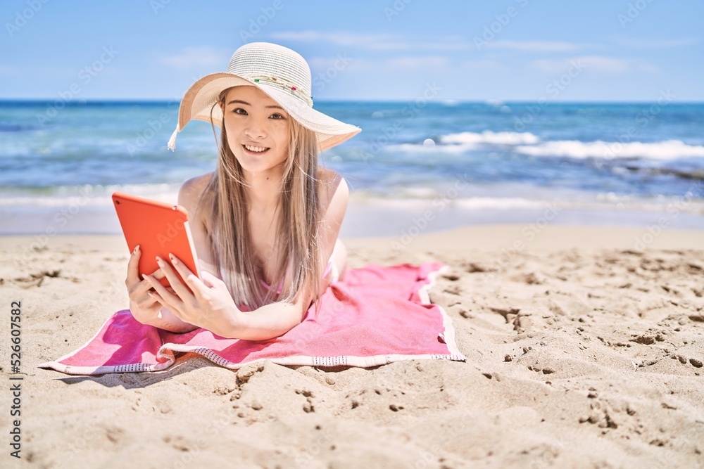 Young chinese girl wearing bikini using touchpad at the beach. Young chinese girl wearing bikini using touchpad at the beach.