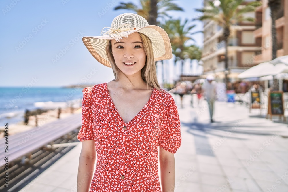 Young chinese girl smiling happy wearing summer hat at the promenade.