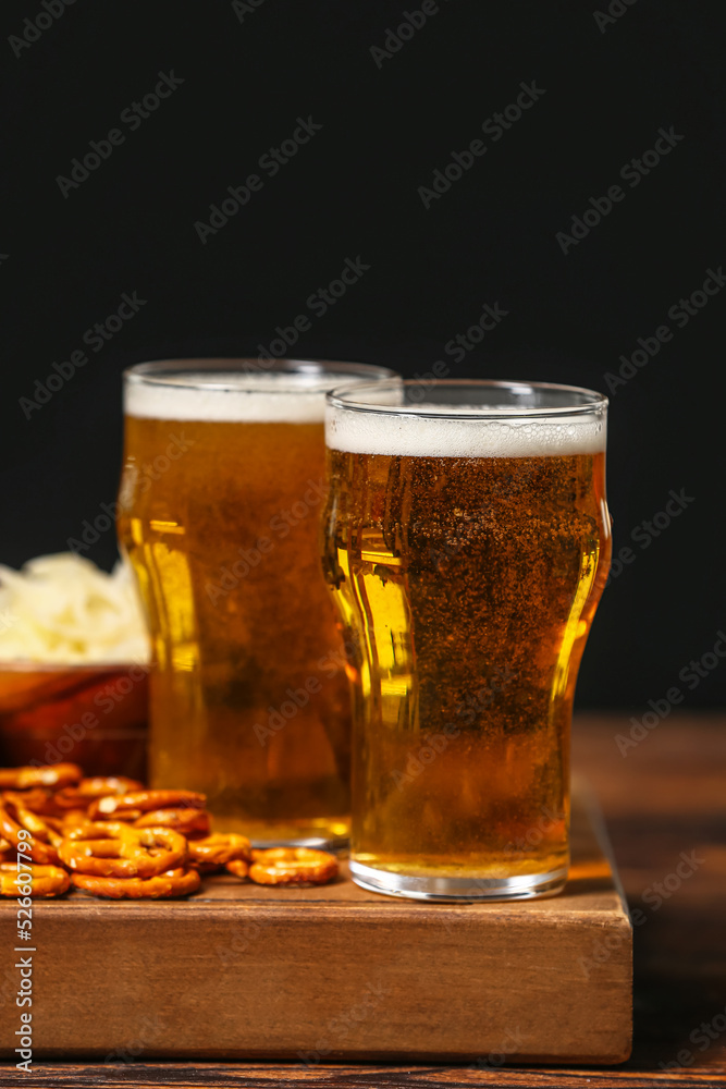 Board with glasses of beer and food on table against dark background. Oktoberfest celebration Board with glasses of beer and food on table against dark background. Oktoberfest celebration