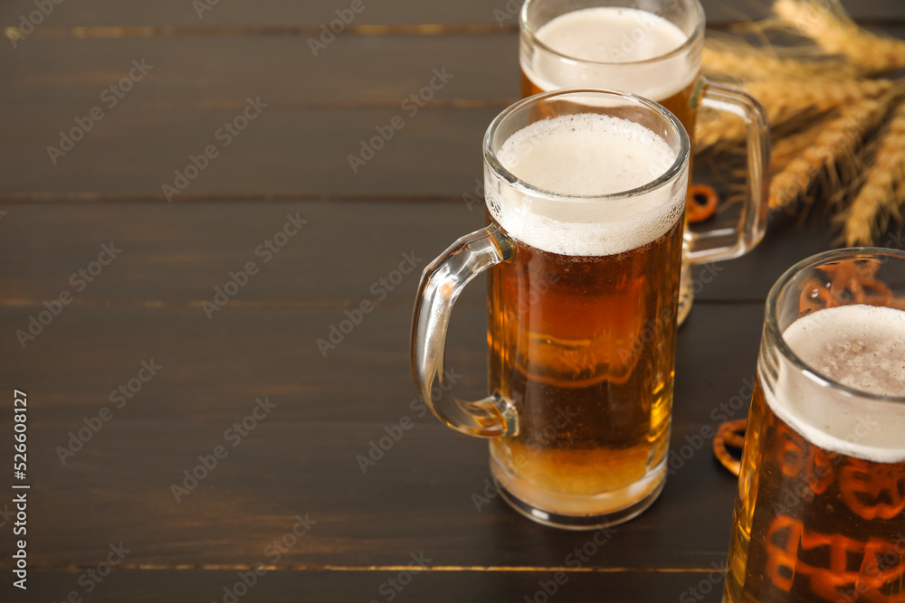 Mugs of fresh beer, pretzels and spikelets on wooden background, closeup. Oktoberfest celebration Mugs of fresh beer, pretzels and spikelets on wooden background, closeup. Oktoberfest celebration
