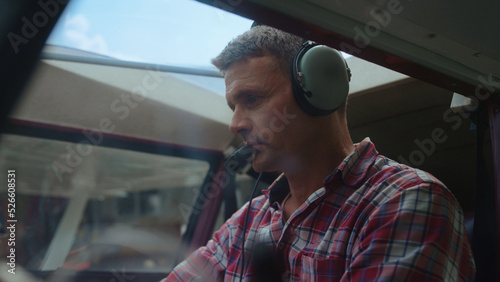 Tela Airman starting airplane engine sitting cockpit with headphones on head closeup