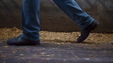 Farmer legs walking cowshed on straw closeup. Worker feet going near stalls.
