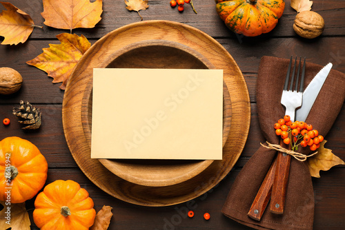 Fototapeta Naklejka Na Ścianę i Meble -  Top view of seasonal table setting with pumpkins and autumn leaves on wooden background, space for text. Thanksgiving Day