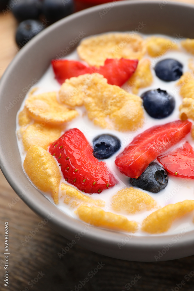 Bowl of tasty crispy corn flakes with milk and berries on wooden table, closeup Bowl of tasty crispy corn flakes with milk and berries on wooden table, closeup