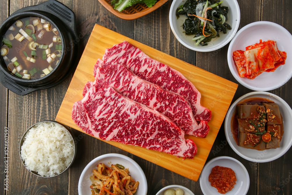 Beef chuck flap tail and side dishes in the background 나무배경에 소고기 살치살과 밑반찬들 Beef chuck flap tail and side dishes in the background 나무배경에 소고기 살치살과 밑반찬들