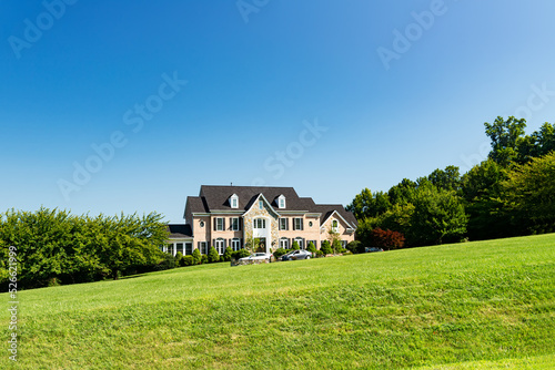 Large country house and summer landscape with a perfect lawn. Blue sky and white clouds.