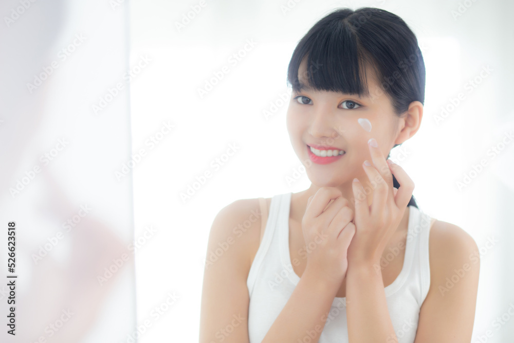 Beautiful young asian woman looking in mirror and apply moisturizer with cosmetic cream or lotion in bathroom at home, skincare for hygiene, treatment and bodycare, skin and anti-aging of facial. Beautiful young asian woman looking in mirror and apply moisturizer with cosmetic cream or lotion in bathroom at home, skincare for hygiene, treatment and bodycare, skin and anti-aging of facial.