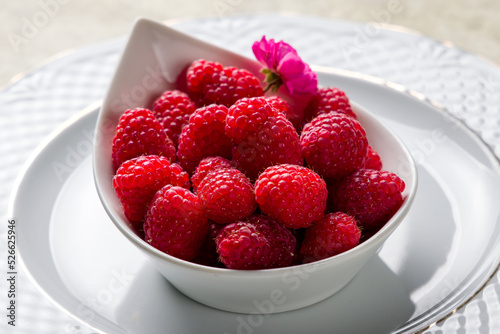 Fresh raspberry on white plate on stone table macro close up
