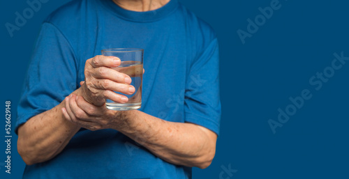 Close-up of hands senior woman trying to hold a glass of water