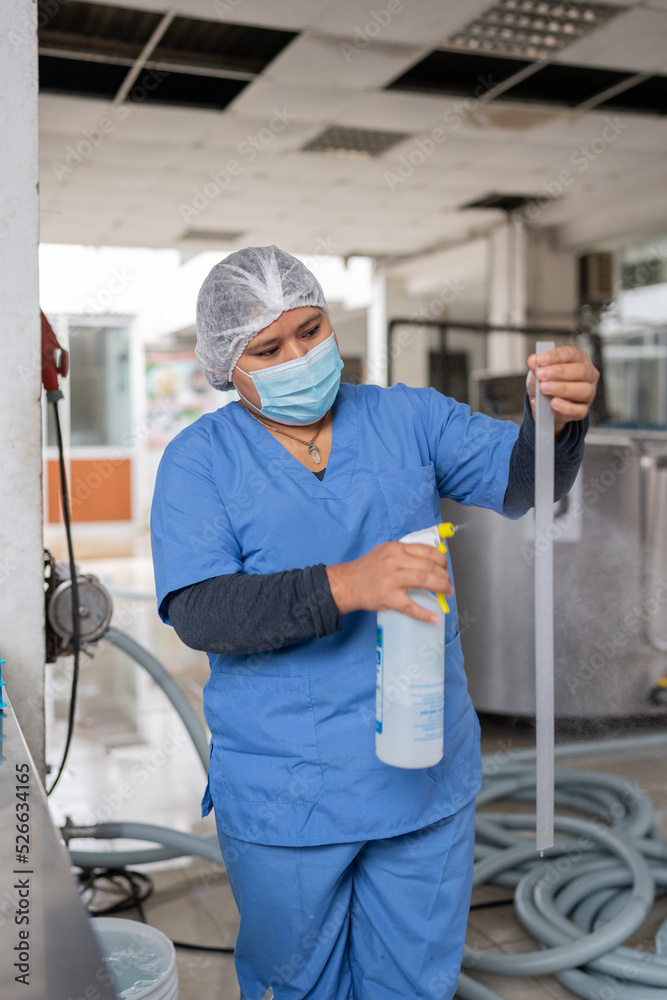 Worker in a dairy processing industry cleaning the equipment