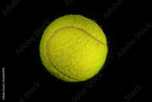 Fuzzy yellow tennis ball photographed in closeup detail against a dark background © Peter