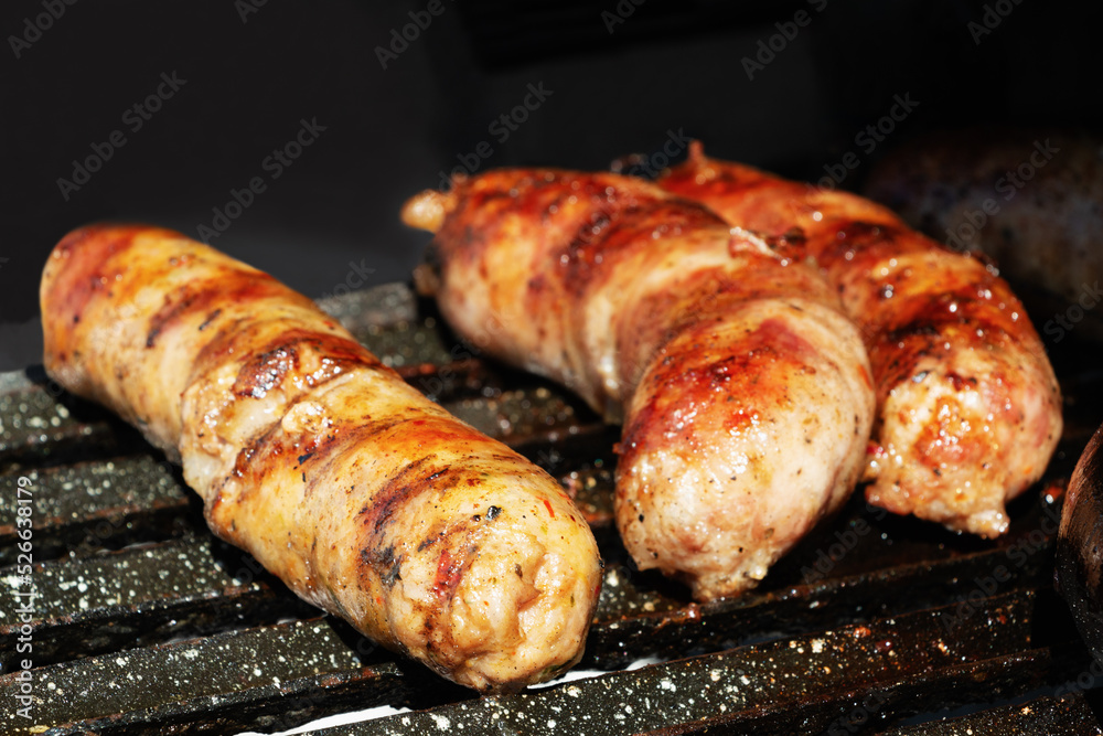 Three sausages cooking on the barbecue grill