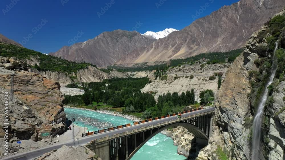 Drone shot of turquoise blue water river flowing under a bridge in Karakoram mountain range along Karakoram highway, slowly revealing