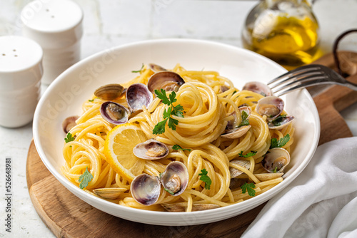 Italian pasta spaghetti with clams and lemon or Spaghetti alle vongole verace, cooked with oil, white wine, garlic, parsley. Selective focus. photo