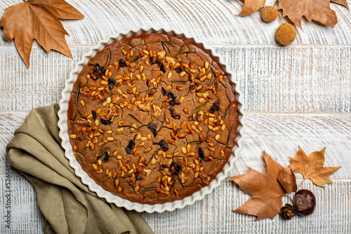 Tuscan vegan autumn chestnut cake Castagnaccio. Made with water, olive oil, pine nuts, rosemary and raisins. Homemade, without wheat flour.  photo