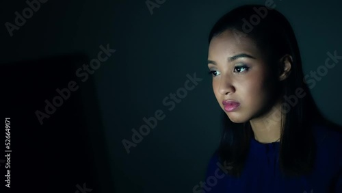 Young Black woman looking screen in dark room. photo