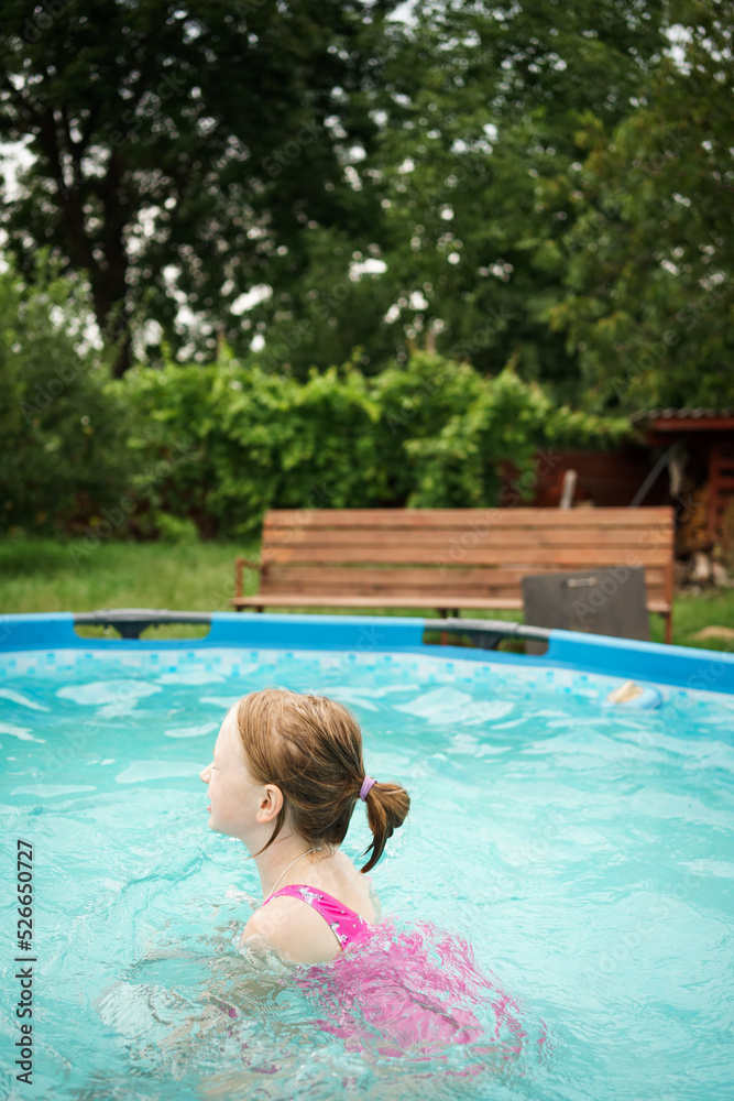 A child in the water. A girl splashes in an inflatable pool in the garden on a sunny summer day. High quality photo