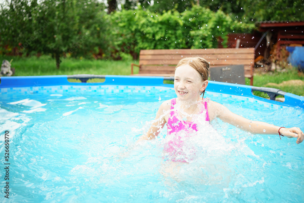 A child in the water. A girl splashes in an inflatable pool in the garden on a sunny summer day. High quality photo