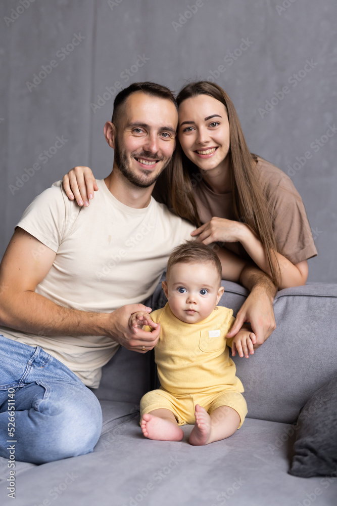 Cheerful family are spending funny time while sitting on sofa in bright room. Happy parenthood concept Cheerful family are spending funny time while sitting on sofa in bright room. Happy parenthood concept