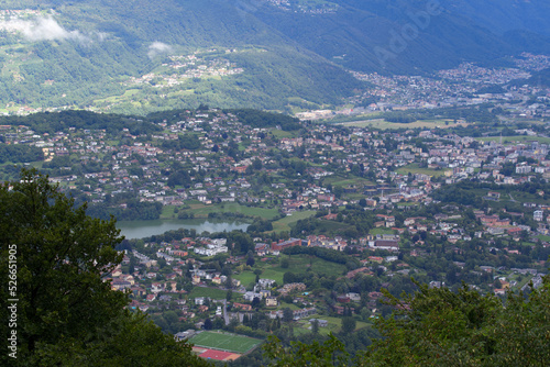 Scenic landscape seen from local mountain San Salvatore, Canton Ticino, over Lake Muzzano on a cloudy summer day. Photo taken July 4th, 2022, Lugano, Switzerland.