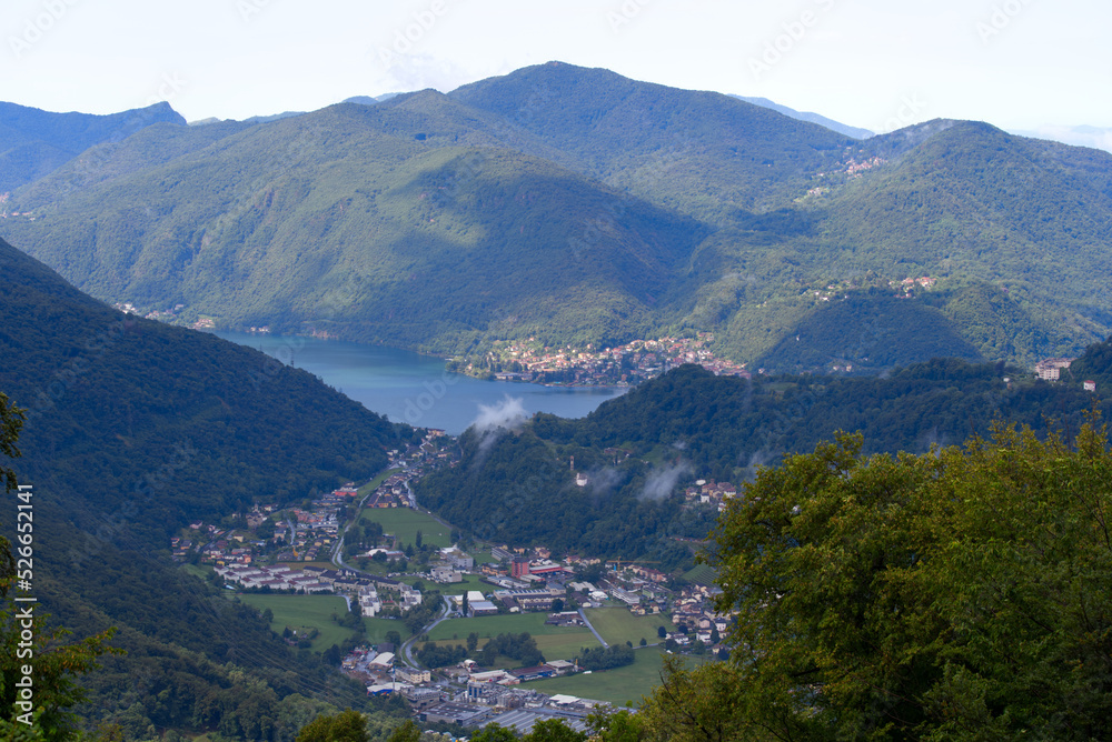 Aerial view from local mountain San Salvatore over region of Lugano, Canton Ticino, with Lake Lugano on a cloudy summer day. Photo taken July 4th, 2022, Lugano, Switzerland.