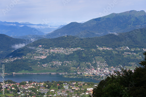 Scenic landscape with mountain panorama and Lake Lugano seen from local mountain San Salvatore at City of Lugano on a cloudy summer day. Photo taken July 4th, 2022, Lugano, Switzerland. © Michael Derrer Fuchs