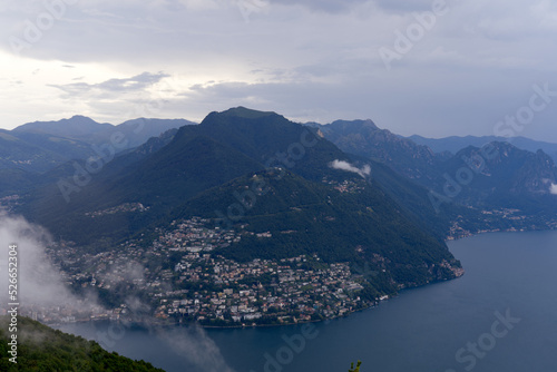 Scenic landscape with mountain panorama and Lake Lugano seen from local mountain San Salvatore at City of Lugano on a cloudy summer day. Photo taken July 4th, 2022, Lugano, Switzerland.