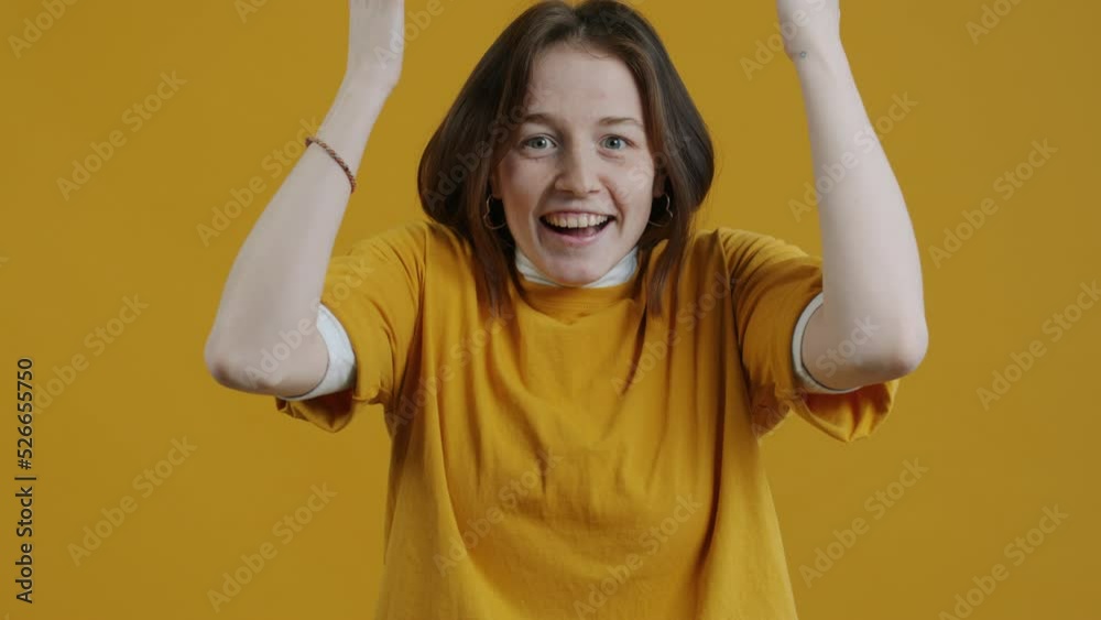 Slow motion portrait of emotional woman feeling excited touching head opening mouth standing on yellow background. People and expressions concept.