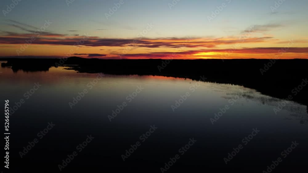 A drone shot made at the Pieni Onkamo lake in Finland. The nightsun shines a red and orange glow on the clouds. A drone shot made at the Pieni Onkamo lake in Finland. The nightsun shines a red and orange glow on the clouds.